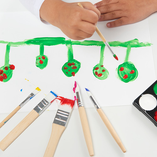 Manos de niños pintando hojas verdes y manchas rojas en papel con pinceles variados.
