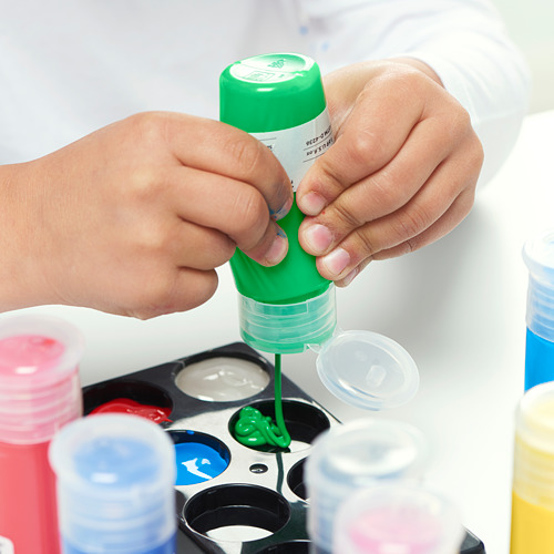 En un niño está exprimiendo la pintura verde MÅLA de una botella en una bandeja para la actividad artística. La pintura está lista para usar y viene en botellas fáciles de exprimir.