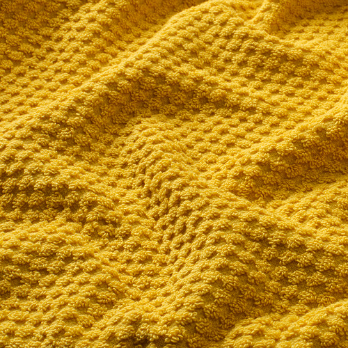 Primer plano de toalla de algodón amarillo suave y texturizado, que muestra su calidad esponjosa y absorbente.