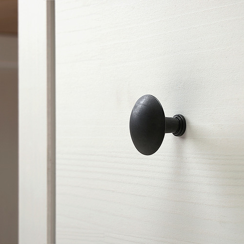 Pomo redondo negro sobre puerta blanca lisa. Diseño elegante, acabado de calidad.