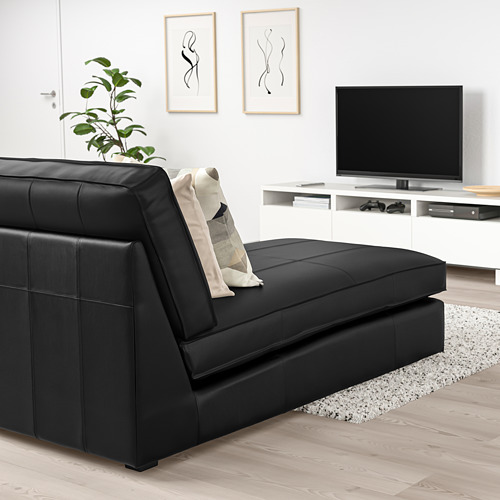 Sala de estar moderna: tumbona KIVIK negra, de estilo, de líneas limpias, con almohadas, planta, tv, arte, suelo de madera clara.