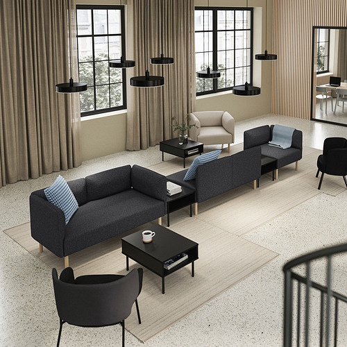 Sala de estar moderna con sofás modulares grises, mesas de centro negras, luces colgantes negras y grandes ventanales con cortinas beige.