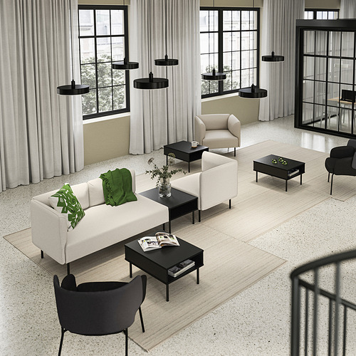 Moderno salón con sofá crema, mesas negras, grandes ventanales.