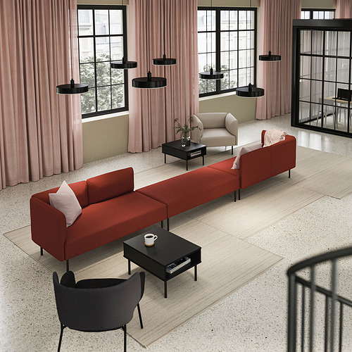 Sala de estar moderna con sofá modular LILLEHEM naranja, mesas de centro negras, lámparas colgantes negras y cortinas rosas.