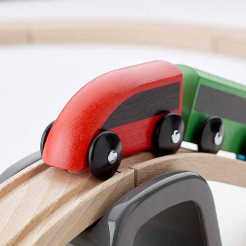 Tren de juguete de madera con vagones rojos y verdes en vía curva. Superficies lisas y pulidas, ruedas robustas y ajuste preciso de la oruga. Artesanía de alta calidad.