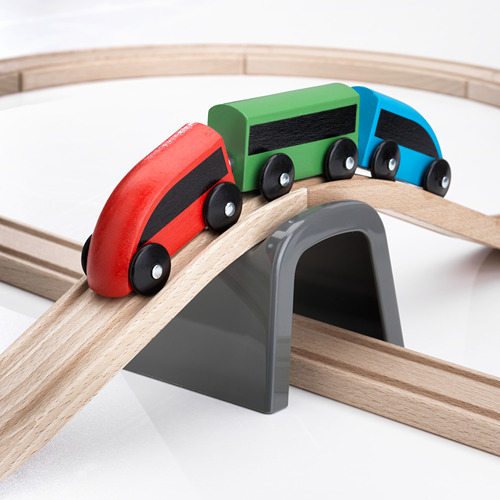 Conjunto de trenes de madera de alta calidad con vibrantes vagones rojos, verdes y azules en las vías, que pasan por un túnel gris.