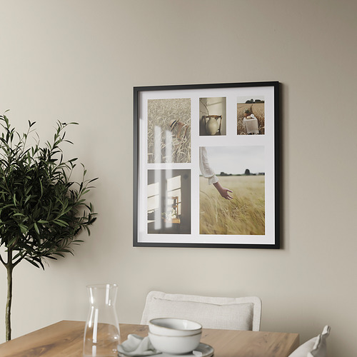 Un marco de fotos montado en la pared, más grande que una silla, muestra cuatro fotos en su interior. Su marco negro contrasta con la pared de color claro.
