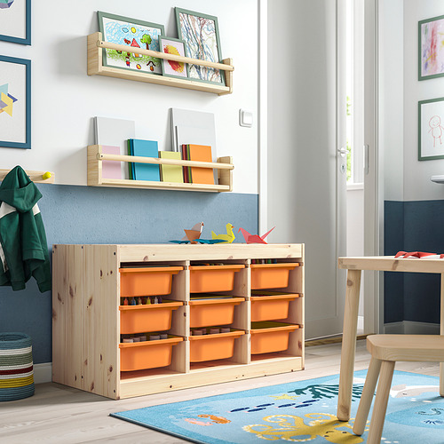 Habitación para niños con almacenamiento de madera clara TROFAST, contenedores de naranja, estantes, alfombra colorida y arte.
