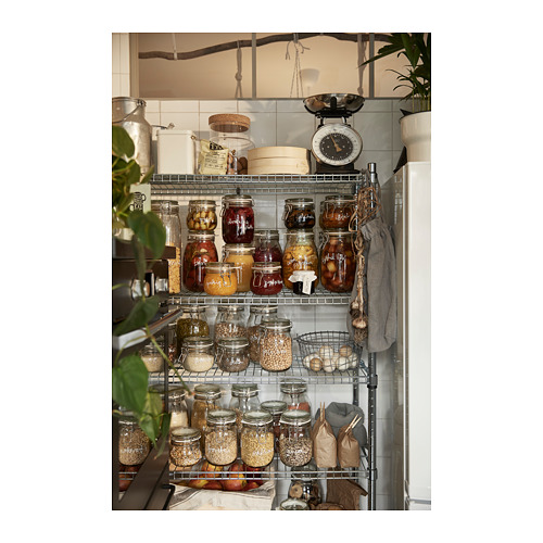 Estantería de cocina con tarros y recipientes, de varios tamaños y colores, organizados con estantes metálicos y plantas colgantes.