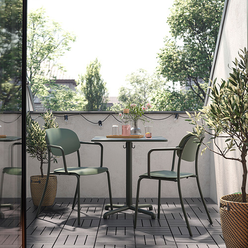 Mesa y sillas de exterior verdes en el balcón con plantas y luces.
