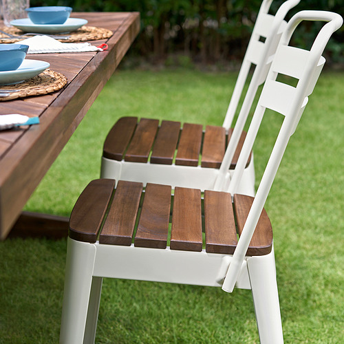 Moderna silla de exterior NORRMANSÖ blanca con asiento y respaldo de madera, diseñada para la comodidad en un entorno de jardín.