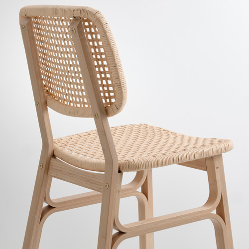 Elegante silla de mimbre con respaldo y asiento curvos, estructura de bambú duradera y tejida por expertos.