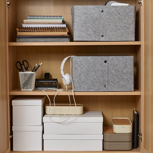 Estantes organizados con cajas de fieltro, artículos de papelería y auriculares para almacenamiento y accesibilidad.