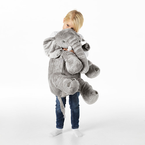 Niño abrazando un gran juguete de peluche de elefante gris, con orejas caídas y colmillos blancos, demostrando su papel como compañero reconfortante y tierno.