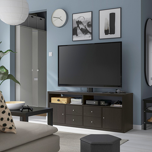 Sala de estar moderna con mueble de TV oscuro KALLAX, pantalla plana grande, sofá gris, mesa de centro y pared azul.
