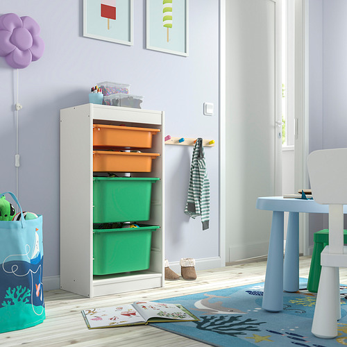 Mueble de almacenamiento TROFAST blanco con compartimentos verdes y naranjas; Habitación de niños con juguetes, libros en alfombra azul, cerca de la mesa, silla.