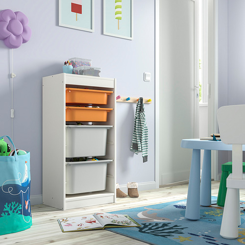 Habitación para niños con unidad de almacenamiento TROFAST blanca, contenedores naranjas y grises, libros y mesa azul.