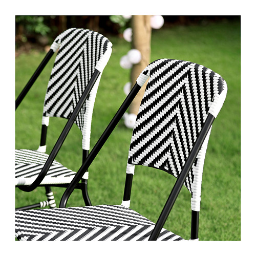 Sillas de exterior tejidas en blanco y negro. Rayas monocromáticas sobre diseño de mimbre con marcos metálicos. Perfecto para patio o jardín.