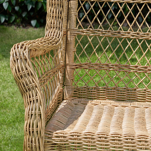 Silla de exterior de mimbre con tejido intrincado, diseñada para la comodidad. Los tonos naturales se mezclan con la vegetación.