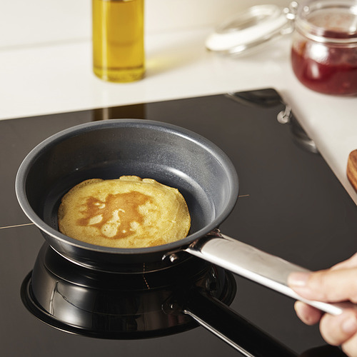 La persona está cocinando panqueques en una sartén antiadherente de ikea en la estufa.