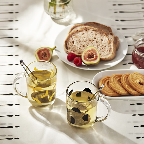 Mesa con dos tazas de té, pan, bollería y frutas. Las asas de las tazas de té muestran un agarre seguro.