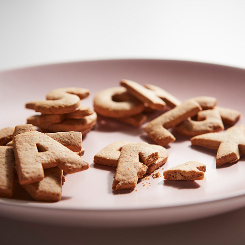 Las galletas en forma de letra de color marrón claro deletrean KAFFEREP en un plato rosa.