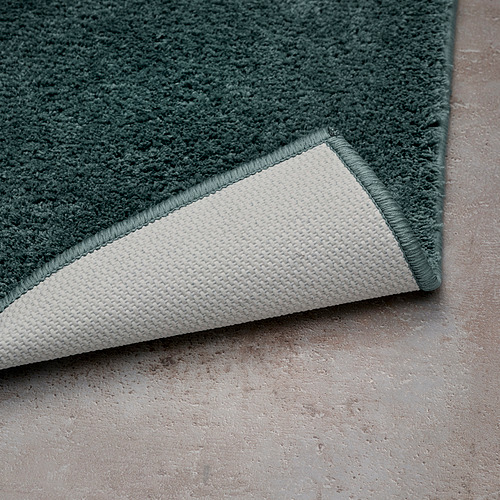 Alfombrilla de baño verde con respaldo blanco, superficie antideslizante.