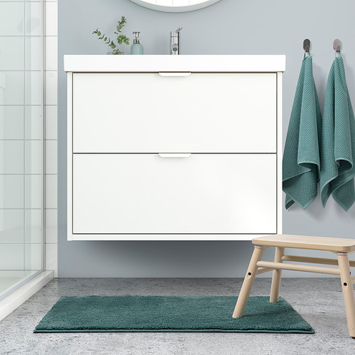 Un baño moderno con una alfombra de baño blanca BACKMÅRA verde azulado junto a un tocador.
