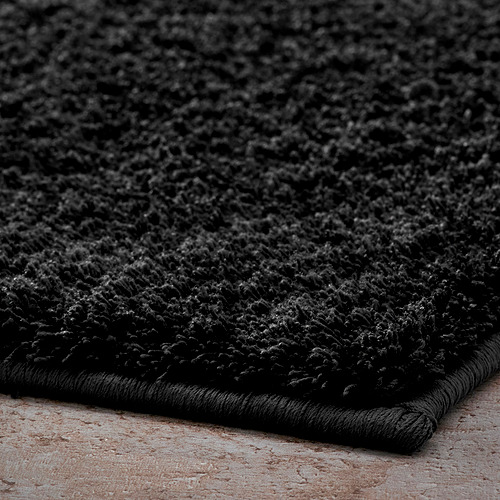 Alfombrilla de baño negra suave y afelpada hecha de poliéster reciclado con respaldo de látex para mayor estabilidad.