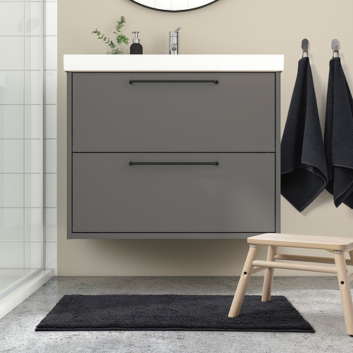 Baño moderno con alfombra de baño gris BACKMÅRA, tocador elegante y toallas. Mat encaja debajo del tocador con detalles en negro.