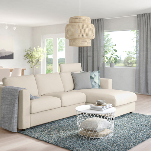 Sala de estar moderna con sofá crema VIMLE, tumbona, cojines de colores, lámpara colgante, mesa auxiliar, alfombra, cortinas, plantas.
