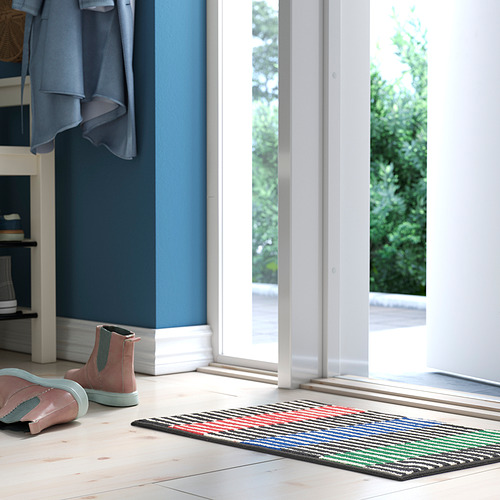 Habitación con pared azul, puerta blanca, alfombra de rayas de colores, botas rosas.