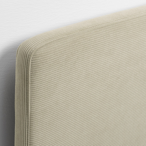 Primer plano de una funda de cabecero de cama suave y texturizada en color beige. Costuras notables y detalle de tela afelpada.
