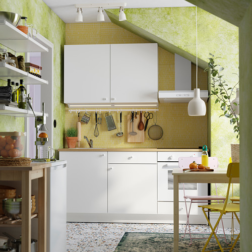 Una cocina moderna de color verde y blanco brillante, gabinetes blancos, un protector contra salpicaduras amarillo y utensilios para colgar.