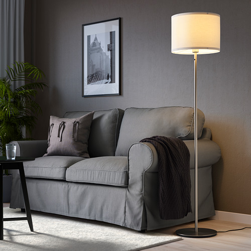 Sala de estar moderna con lámpara SKAFTET, sofá gris, cojines y arte de pared.