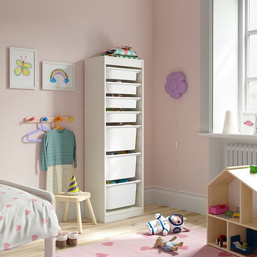 Habitación para niños con almacenamiento blanco TROFAST, paredes rosas, alfombra de corazón, juguetes de madera, animales de peluche y arte colorido.