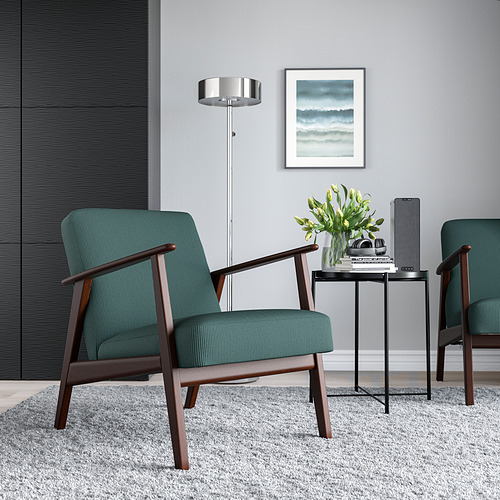 Acogedora sala de estar con dos sillones EKENÄSET verdes, mesa auxiliar, flores y arte retro de playa.