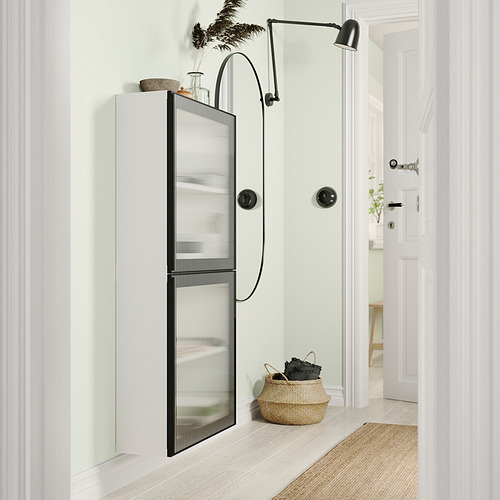 Baño moderno con gabinete blanco, puerta de vidrio esmerilado, manijas negras, canasta tejida y lámpara negra.
