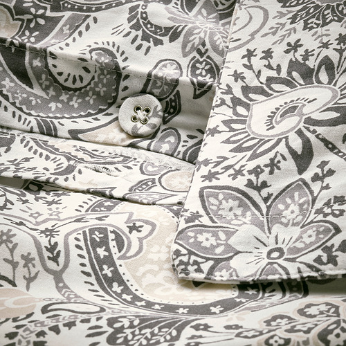 Funda de almohada decorativa de cachemira con motivos florales grises sobre color crema, cerramiento abotonado y cierre de sobre.