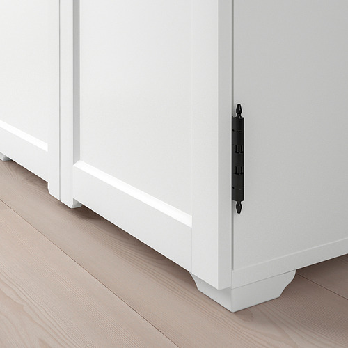 Moderno gabinete blanco con elegantes manijas negras colocadas sobre un piso de madera clara, enfatizando la calidad y el diseño.