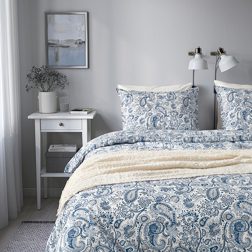 Dormitorio sereno con ropa de cama de cachemira azul, dos lámparas blancas y decoración.