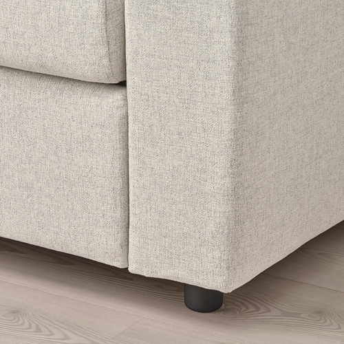Primer plano del sofá: tela suave de color gris claro, cojines de felpa, patas oscuras y resistentes.