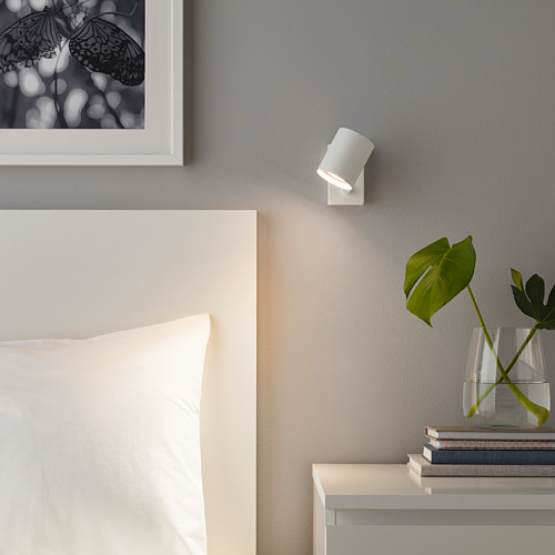 Dormitorio moderno con aplique LED SOLHETA, mesita de noche, almohada, planta y arte de mariposas.