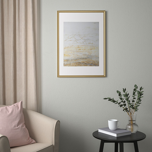 Cuadro abstracto de color blanco dorado SILVERHÖJDEN en la pared, con elegante silla y mesa auxiliar.