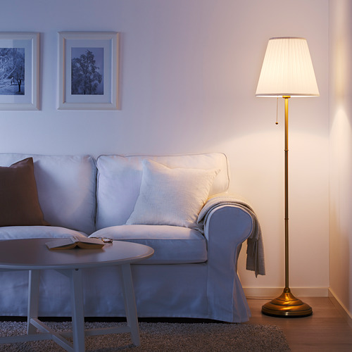 Acogedora sala de estar con lámpara y sofá ÅRSTID azul claro, mesa de centro de madera y arte de pared. Las lámparas de pantalla blanca difunden una luz suave.