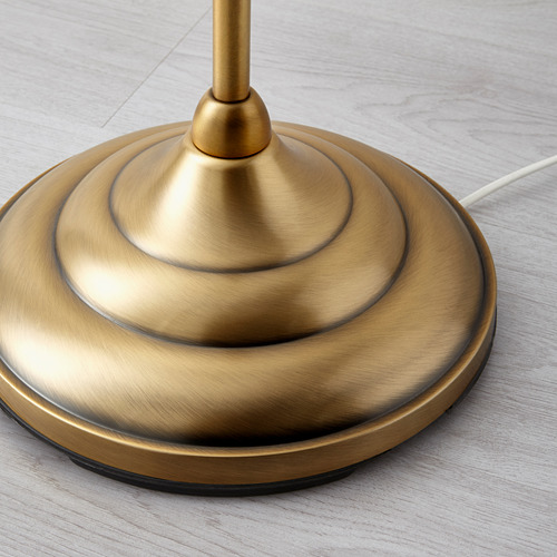 Base de lámpara de metal dorado sobre superficie de madera. Se muestra en primer plano, resaltando el diseño elegante y el acabado de calidad.