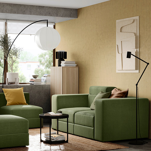 Salón moderno: sofá de pana verde, almohada amarilla, armario de madera, arte abstracto, gran lámpara de pie.