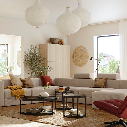 Acogedora sala de estar con sofá modular beige, silla de acento rojo, faroles colgantes y una gran ventana que proporciona luz natural.