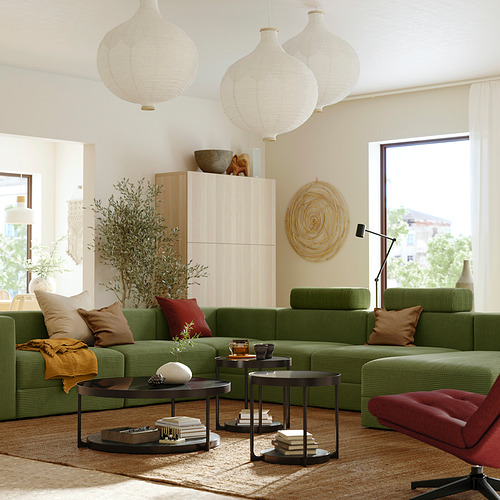 Moderno salón con sofá modular JÄTTEBO verde, lámparas blancas colgantes, armario de madera y gran ventanal.