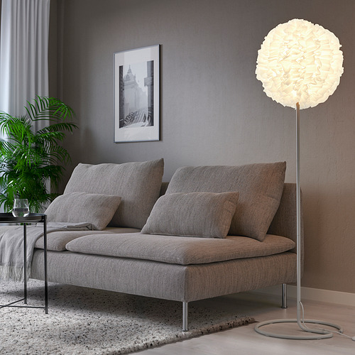 Salón moderno con sofá gris, lámpara alta VINDKAST, arte y planta.